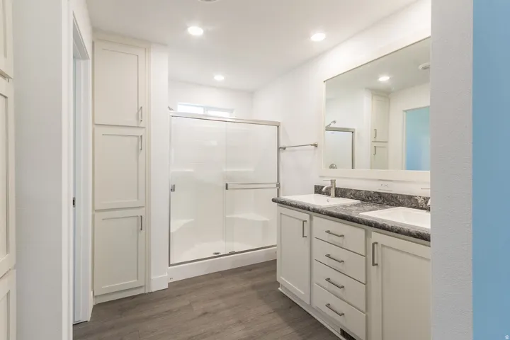 Bathroom featuring a dual vanity with white cabinetry and dark countertops