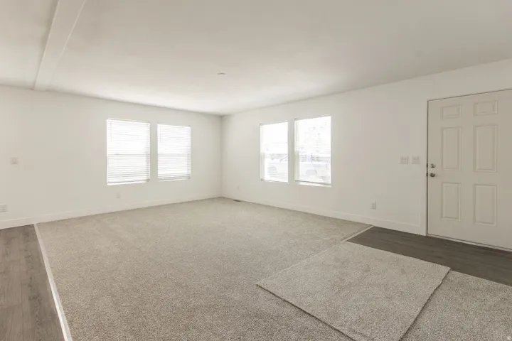 Spacious main living area featuring neutral carpeting and white walls