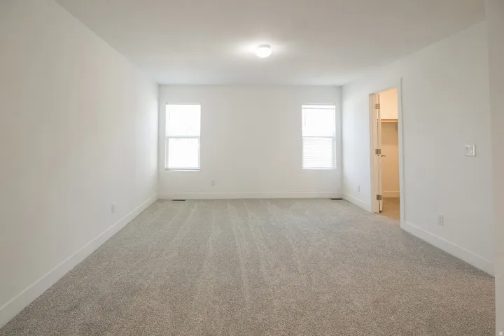 Spacious room with light-toned wall-to-wall carpeting and crisp white walls