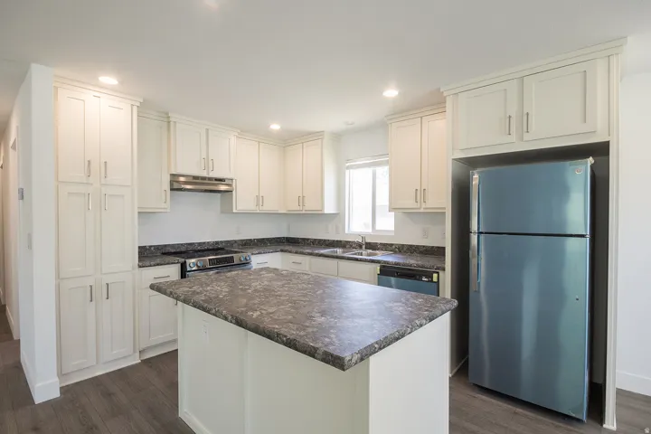 Kitchen featuring white cabinetry, dark speckled countertops, a central island, recessed lighting, and wood-finish flooring