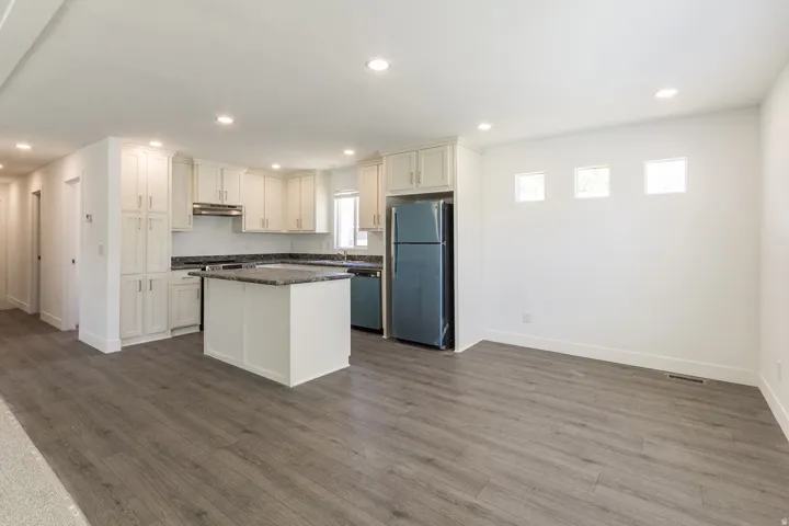 Open-concept kitchen and living area featuring wood-finish flooring, recessed lighting, and white walls