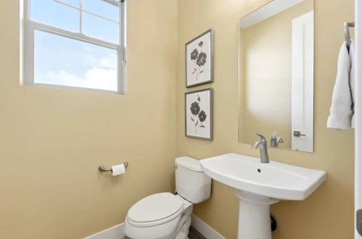 Pedestal sink with chrome faucet, complemented by a rectangular frameless mirror