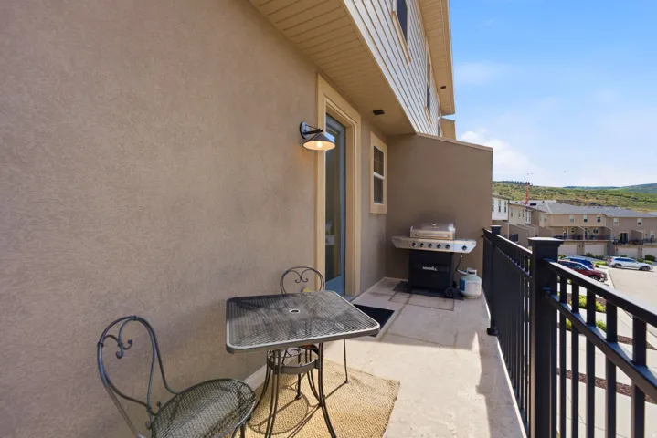 Private balcony featuring stucco exterior, concrete flooring, and black metal railing