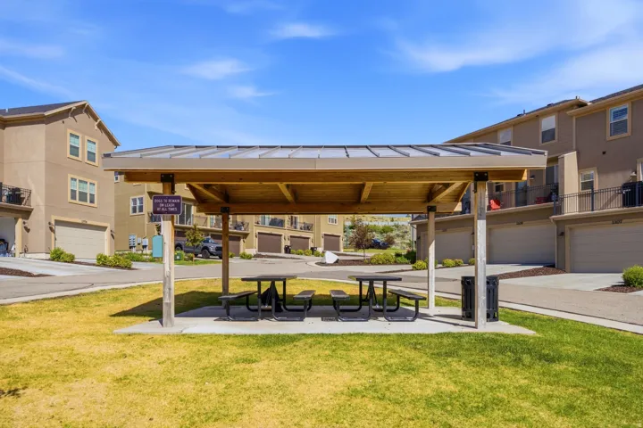 Central park space featuring a covered pergola with two picnic tables and an integrated waste receptacle