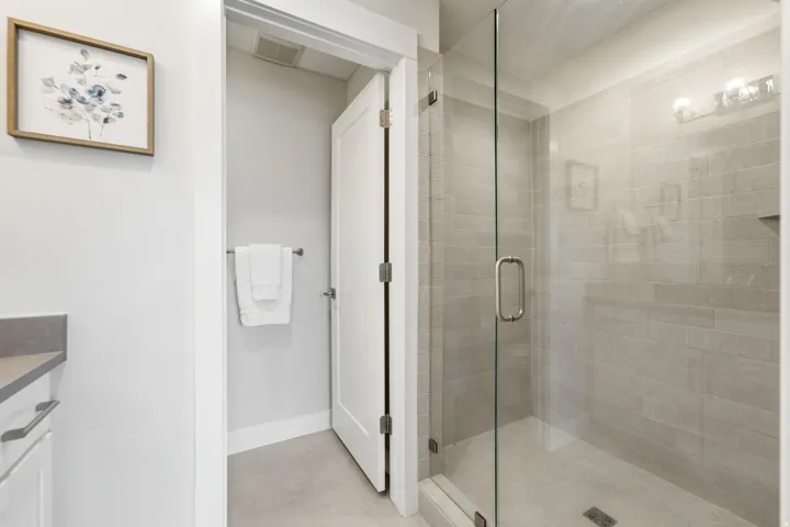 Glass-enclosed shower featuring light grey subway tile and a built-in shower niche