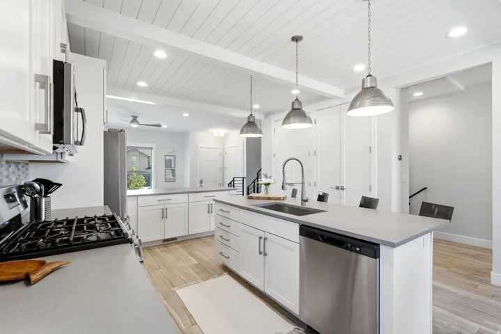 Modern kitchen featuring white cabinetry, light countertops, wood-finish flooring, stainless steel appliances, and a shiplap ceiling with recessed lighting