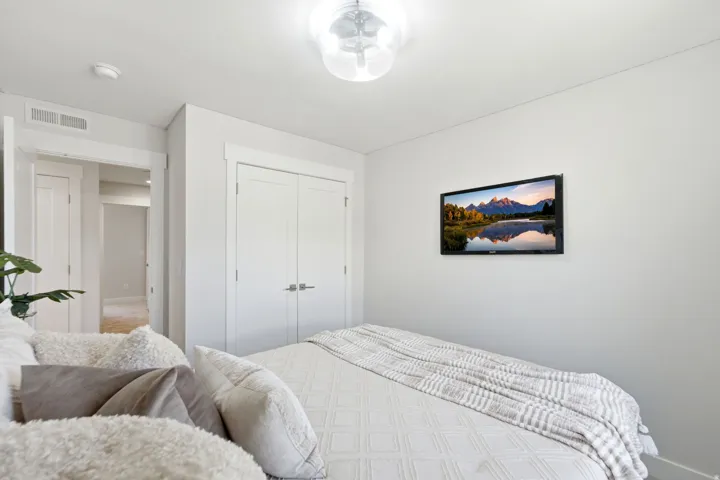 Recessed lighting, light-colored walls, and a ceiling-mounted light fixture illuminate this room featuring white trim and a double-door closet