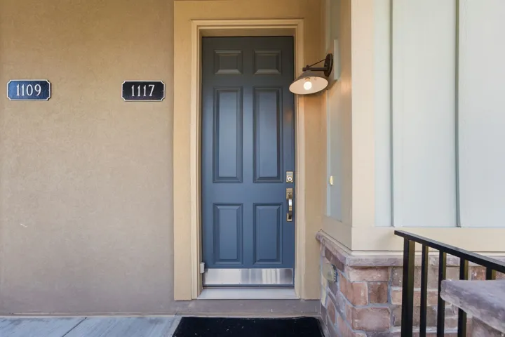 Entryway featuring a paneled door, wall-mounted light fixture, and contrasting stone facade base