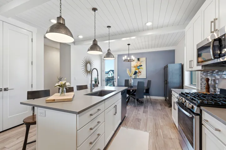 Contemporary kitchen featuring white cabinetry, stainless steel appliances, and a central island with a sink
