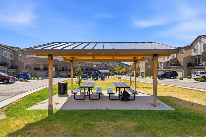 Community gathering area featuring a covered picnic structure with a metal roof and wooden supports