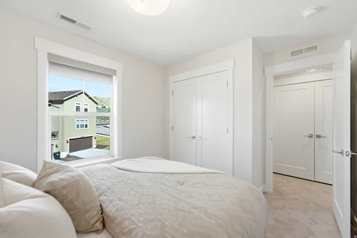 Bedroom featuring a large window, neutral carpeting, and a ceiling light fixture
