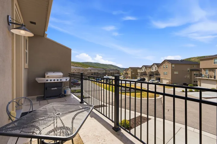 Private outdoor patio with a black metal railing and exterior wall sconce