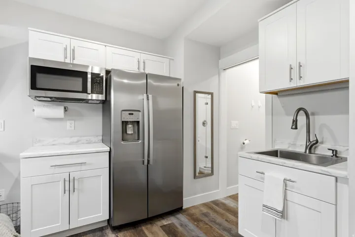 Compact kitchen area featuring white shaker cabinetry and a stainless steel side-by-side refrigerator