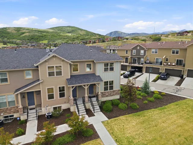 Modern townhome with multi-tone exterior siding, stone accents, and dark pitched roofs
