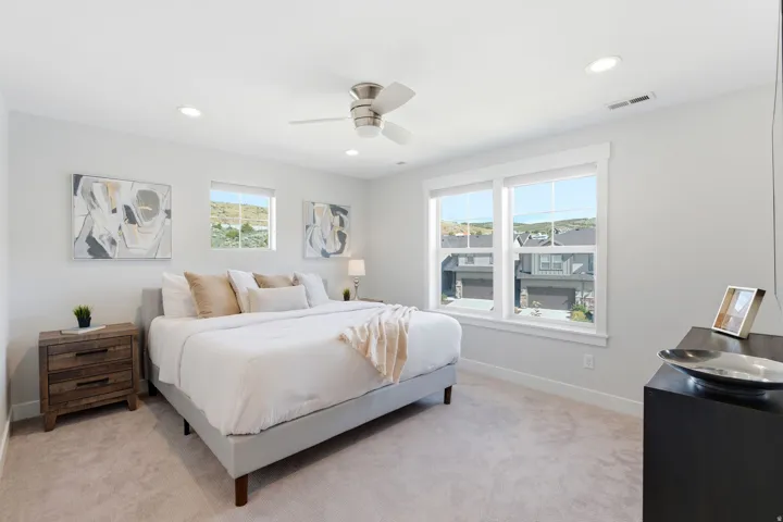Bright bedroom featuring three windows, a ceiling fan with integrated lighting, recessed lighting, and light-toned carpet flooring