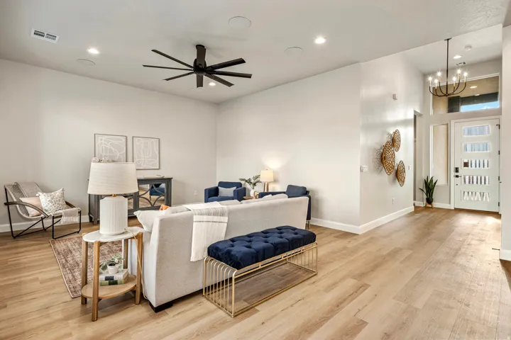 Spacious living area featuring light wood-finish flooring, a contemporary ceiling fan, recessed lighting, and high ceilings