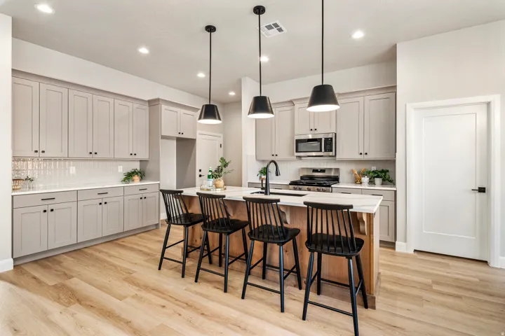 Modern kitchen featuring light-toned cabinetry, a spacious island with counter seating, light wood-finish flooring, recessed lighting, and stylish pendant fixtures