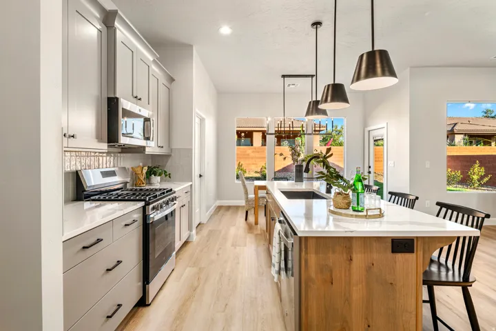 Kitchen featuring light wood-finish flooring, light gray cabinetry with black hardware, stainless steel appliances, and white countertops