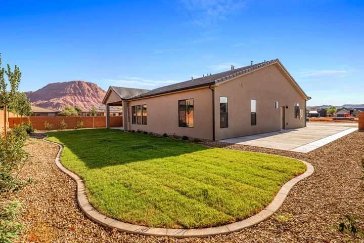 Expansive backyard featuring a manicured lawn, gravel landscaping, and a concrete patio
