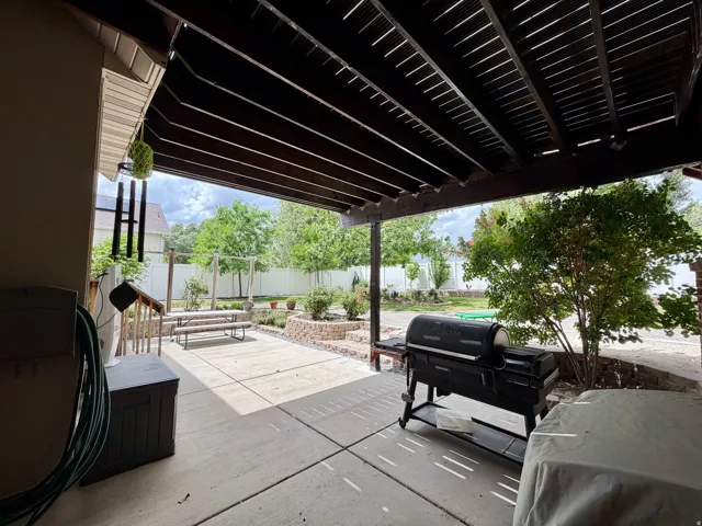 Covered patio with concrete flooring, slatted wood ceiling, and a built-in planter