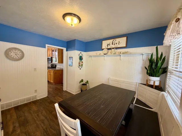 Dining area featuring wood-finish flooring, beadboard wainscoting, and a built-in bench seating arrangement