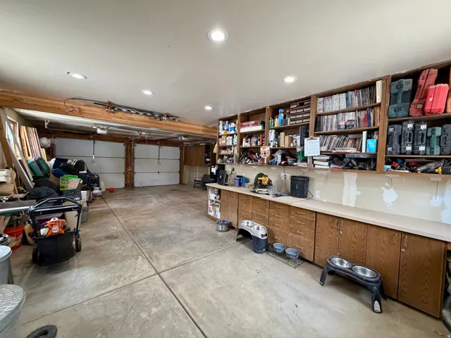 Spacious two-car garage featuring a concrete floor, built-in cabinetry with a light-toned countertop, integrated shelving, and recessed lighting
