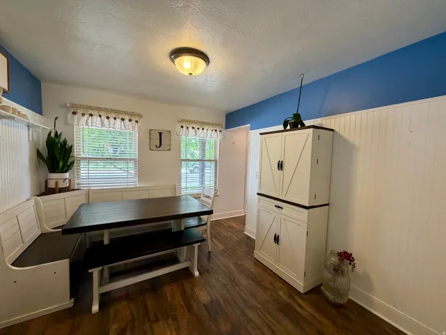 Dining space featuring wood-finish flooring, white beadboard wall paneling, and a two-tone wall treatment