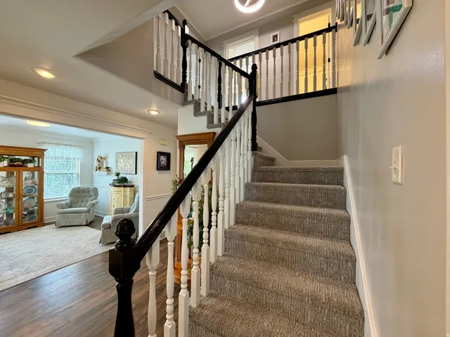 Carpeted staircase featuring a painted wood balustrade with a contrasting handrail