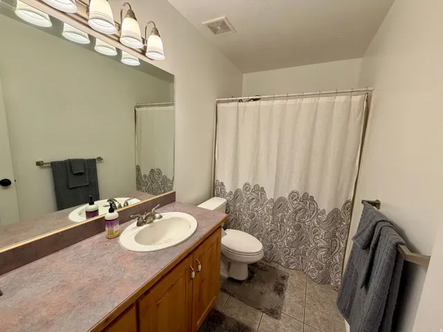 Bathroom featuring a vanity with wood cabinetry and a patterned countertop