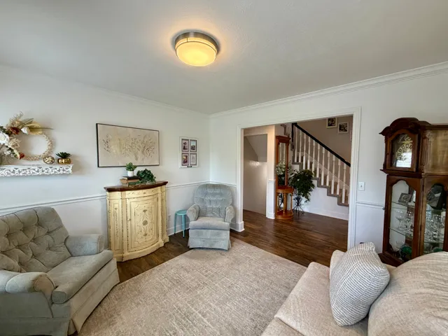 Living area with wood-finish flooring, crown molding, and wainscoting