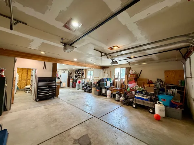 Spacious garage with concrete flooring, exposed wood beams, and multiple overhead light fixtures