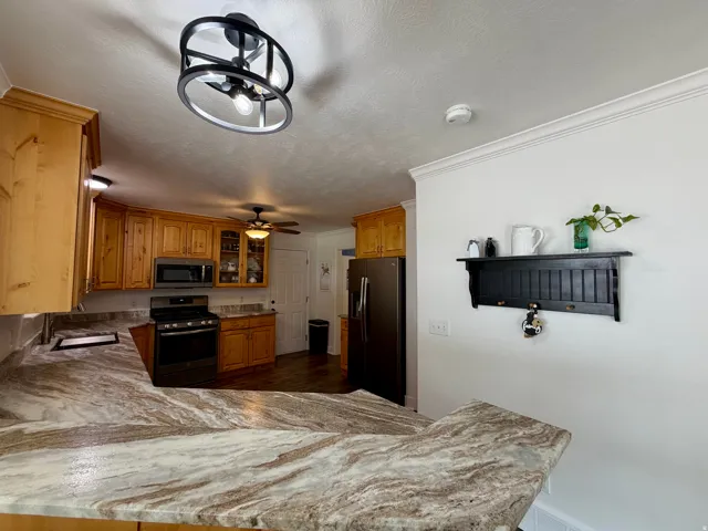 Kitchen featuring a spacious counter with a multi-toned surface, ample cabinetry with glass-front accents, and a built-in microwave