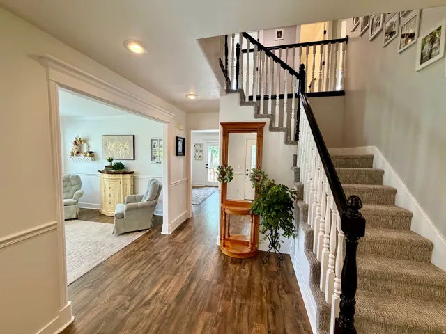 Foyer featuring wood-finish flooring, recessed lighting, and a staircase with carpeted treads and a white and black baluster railing