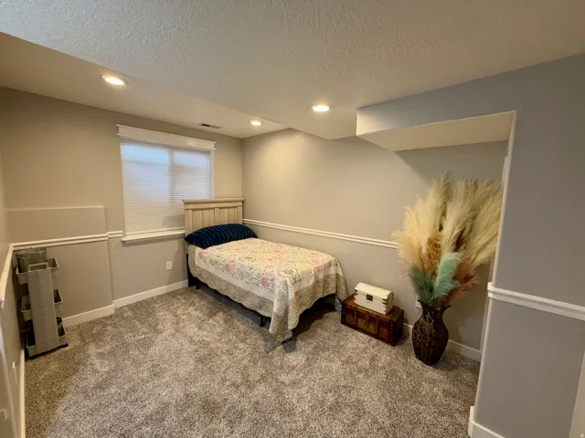 Carpeted room featuring a window with blinds, recessed lighting, and crown molding accents