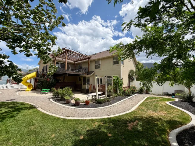 Expansive backyard featuring a manicured lawn, gravel pathways, and mature trees