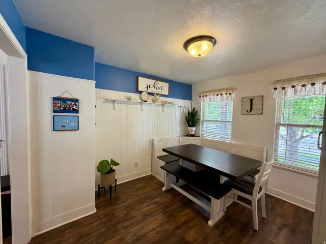 Dining area featuring wood-finish flooring, white beadboard paneling, and a built-in bench