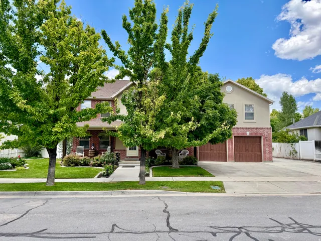Two-story residence featuring a brick and stucco exterior, a two-car garage with wood-finish doors, a concrete driveway, and a front walkway