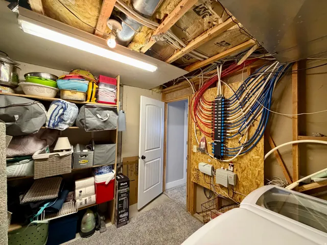 Utility room featuring exposed ceiling joists and ductwork, a PEX manifold system, and a white paneled door