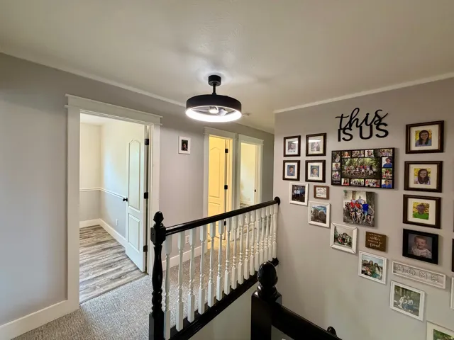 Upper-level landing featuring a contemporary flush-mount light fixture, carpet flooring, and a black and white baluster railing
