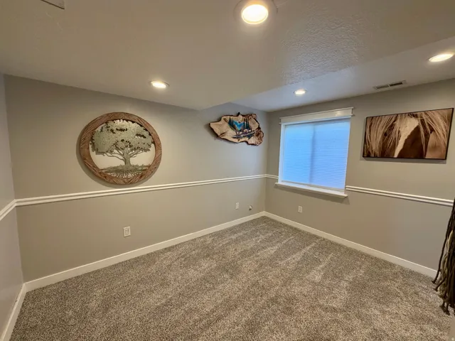 Carpeted room featuring recessed lighting, a window with blinds, and decorative wall trim