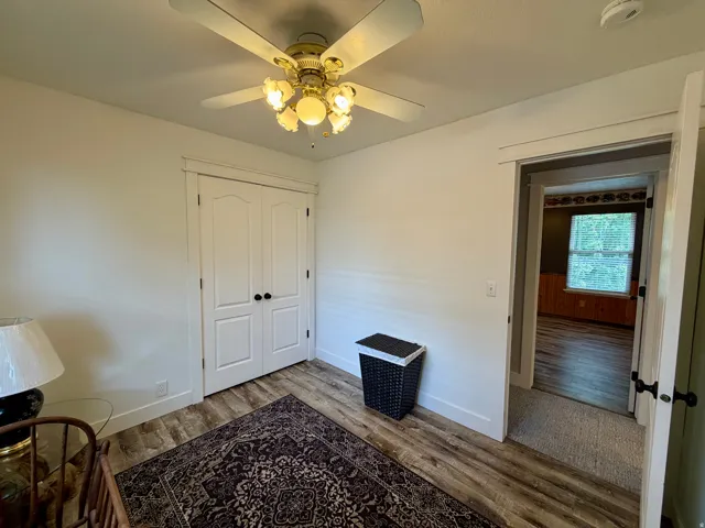 Bedroom featuring wood-finish flooring, white walls, and a ceiling fan with integrated lighting