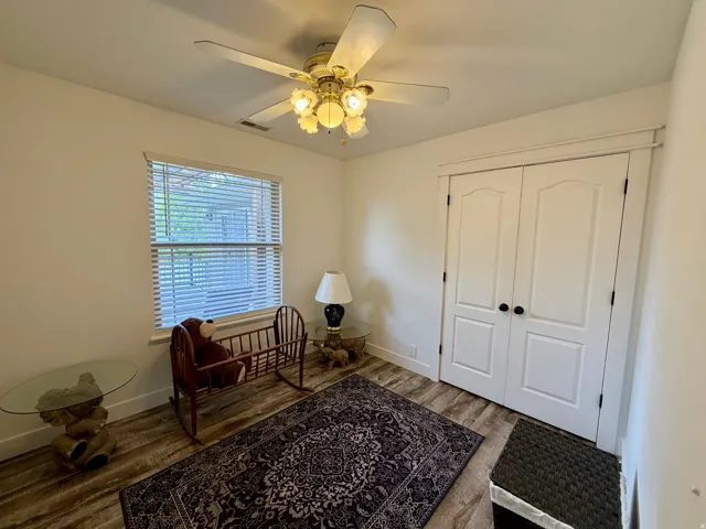 Interior room featuring wood-finish flooring, white walls, and a ceiling fan with integrated lighting
