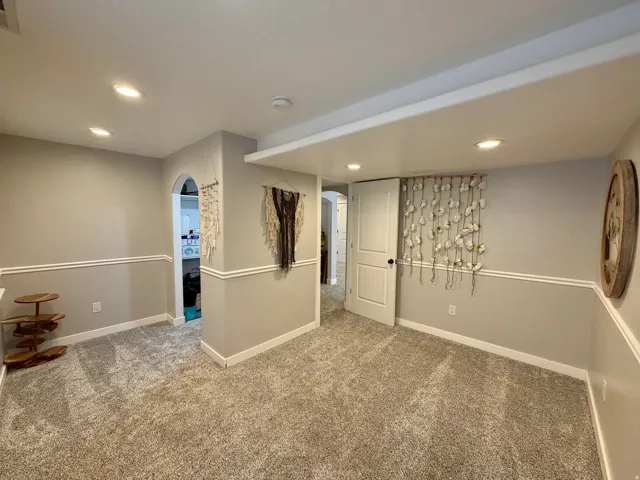Carpeted interior space featuring recessed lighting, a chair rail, and an arched doorway