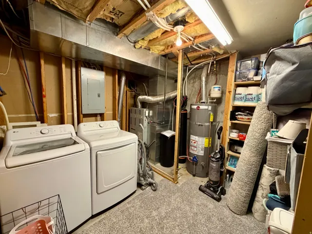 Dedicated utility area featuring a washer and dryer, exposed ceiling joists, and visible mechanical systems