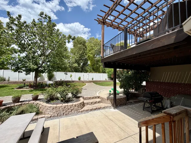 Expansive backyard featuring a multi-level design with a concrete patio, stone retaining walls, and a manicured lawn