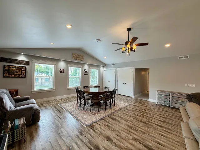 Spacious room featuring vaulted ceilings, recessed lighting, wood-finish flooring, and multiple windows