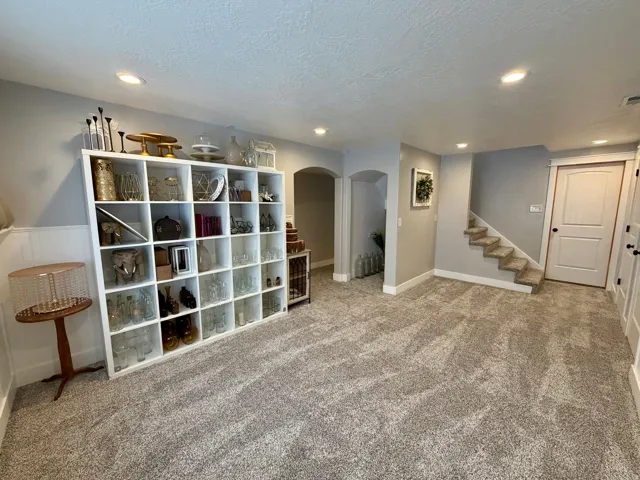 Spacious room with plush gray carpeting, recessed lighting, white baseboards, and a neutral wall color