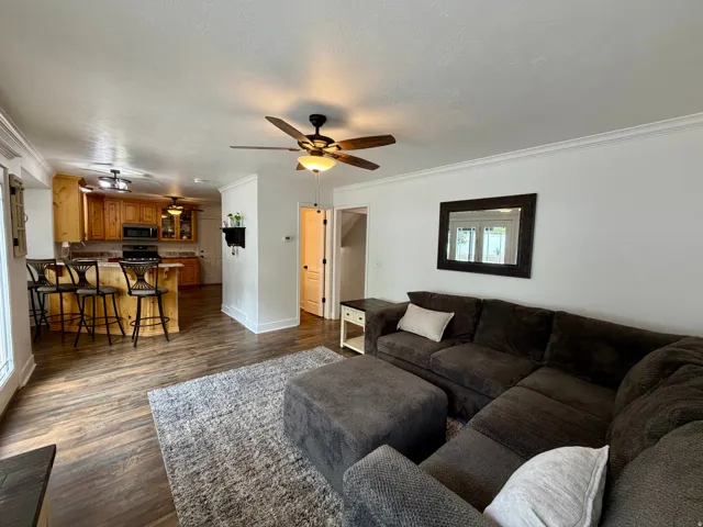 Open-concept living space with wood-finish flooring, white crown molding, and recessed lighting