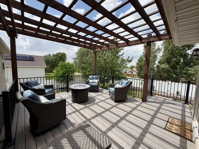 Expansive deck featuring composite decking, a wood pergola, and black metal railing