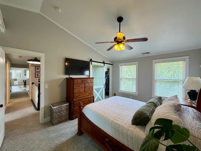 Vaulted ceiling bedroom featuring carpet flooring and two windows with blinds